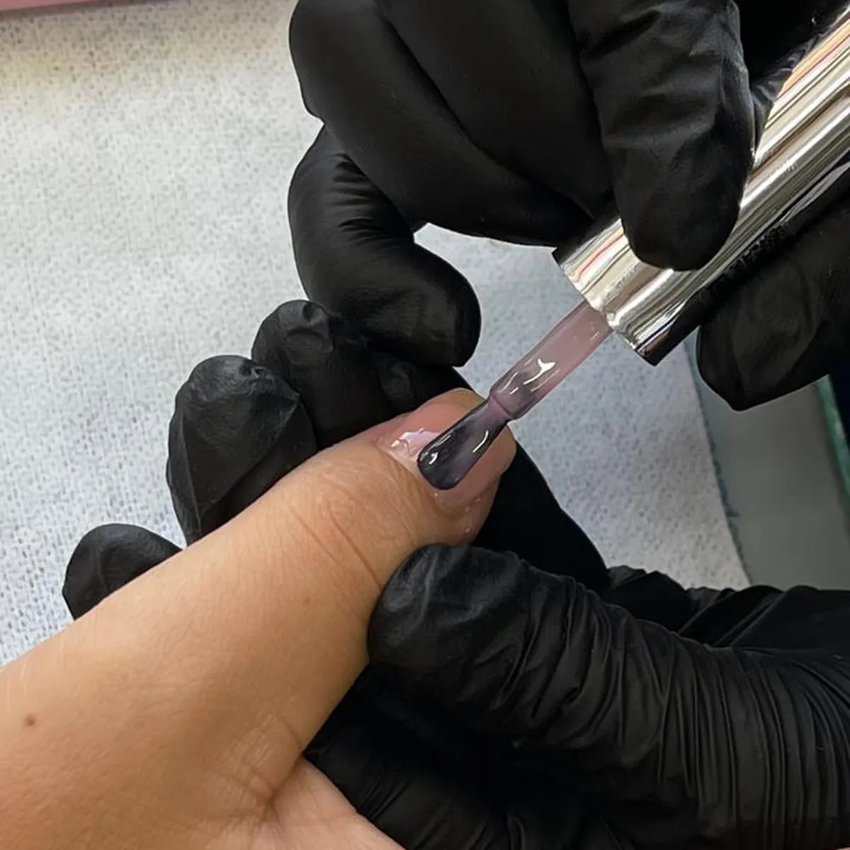 Uñas con esmaltado rojo profesional junto a frasco de esmalte sobre fondo blanco limpio