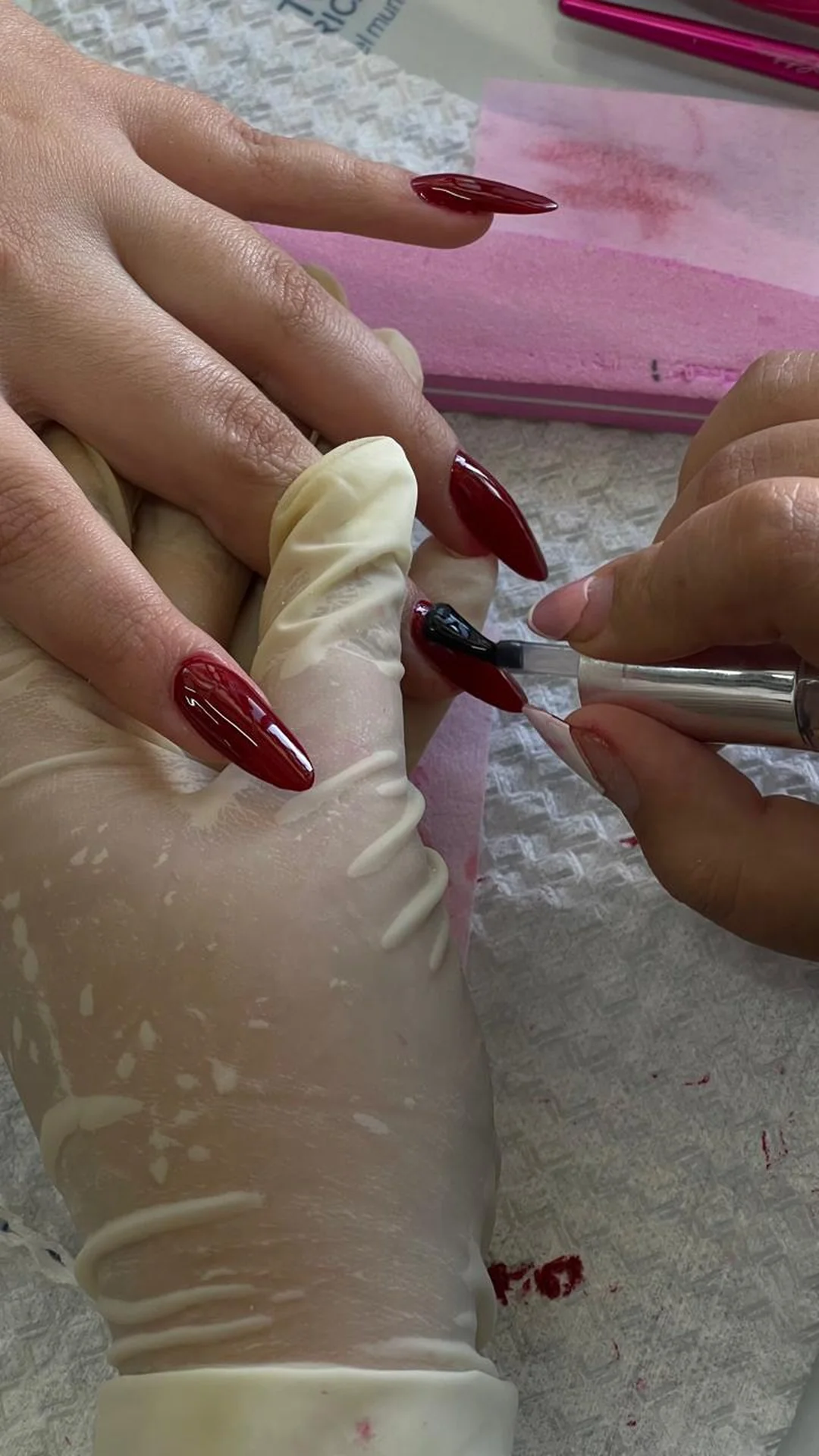 Detalle de esmaltado rojo profesional con acabado brillante y técnica de precisión en manicura estética